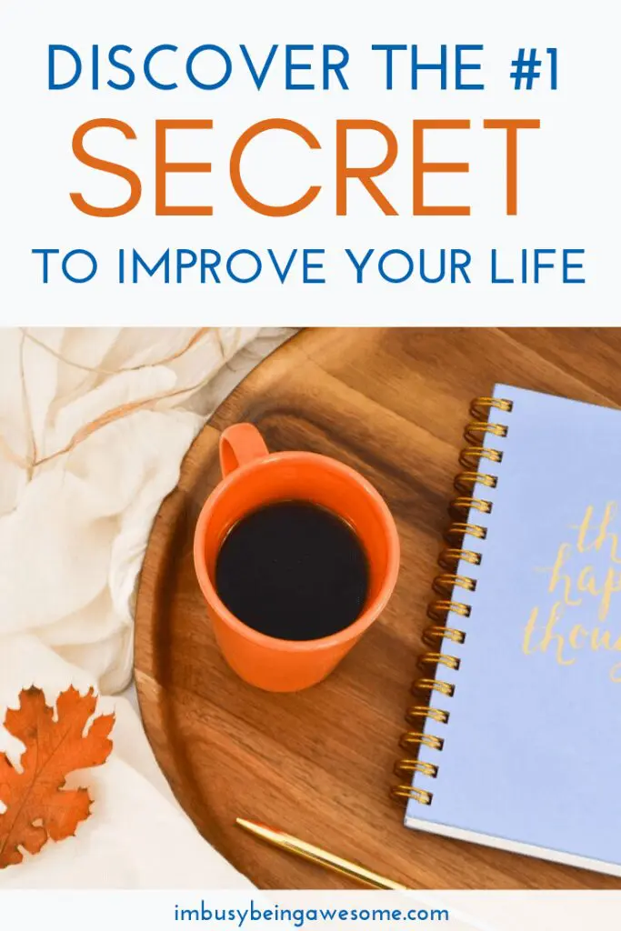 Orange mug with coffee, notebook with "happy thoughts," pen, and autumn leaf on a wooden tray.