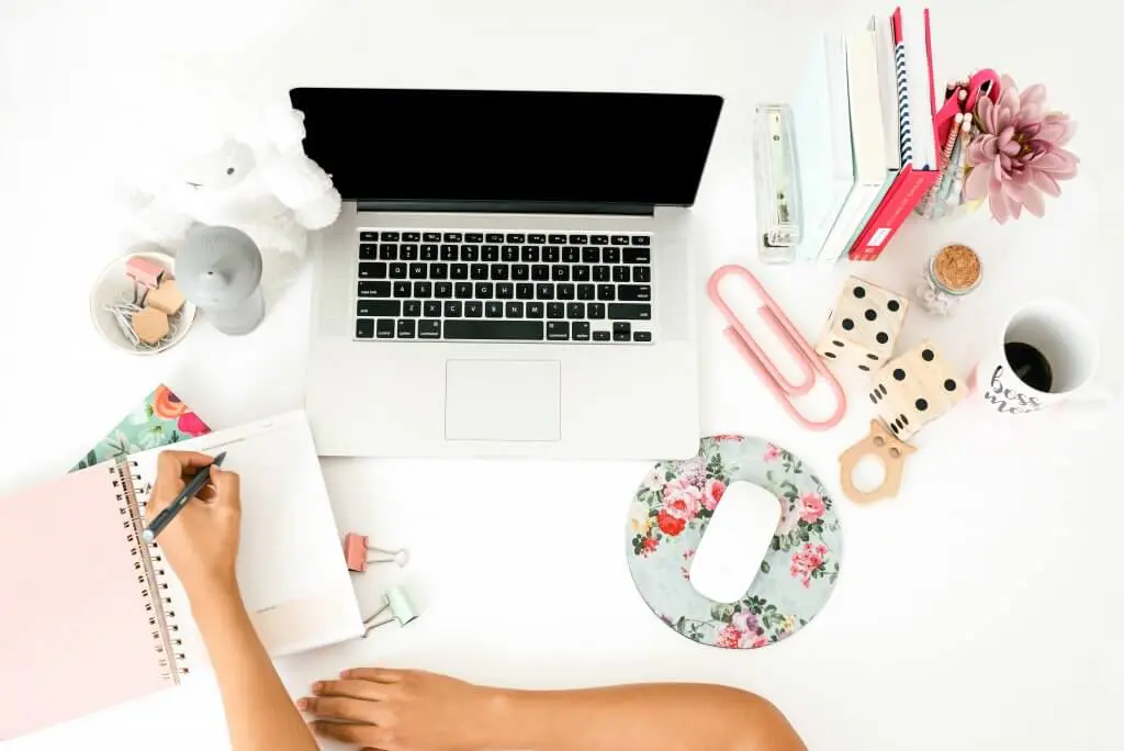 Desk with laptop, notebook, and accessories. Could represent time management or a fresh start.