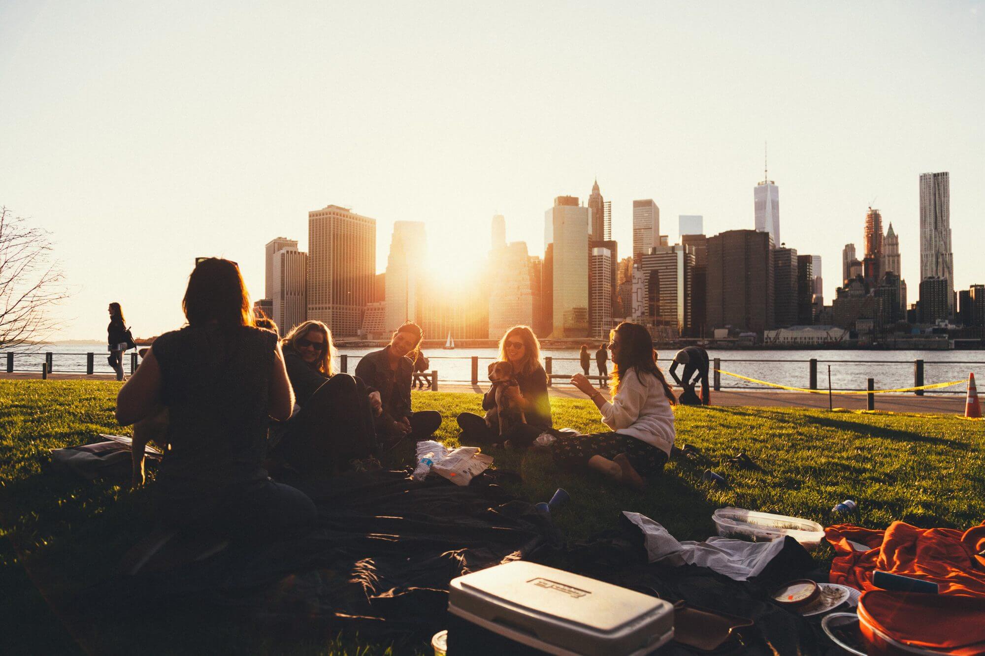 Friends having a picnic with the NYC skyline at sunset.