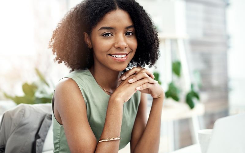 Smiling woman ready to achieve goals with ADHD, sitting at a desk.