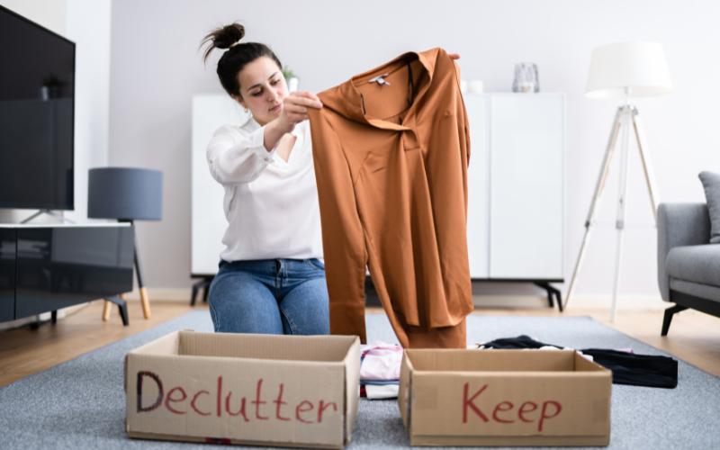 Woman decluttering clothes for spring cleaning with ADHD, with "Declutter" and "Keep" boxes.