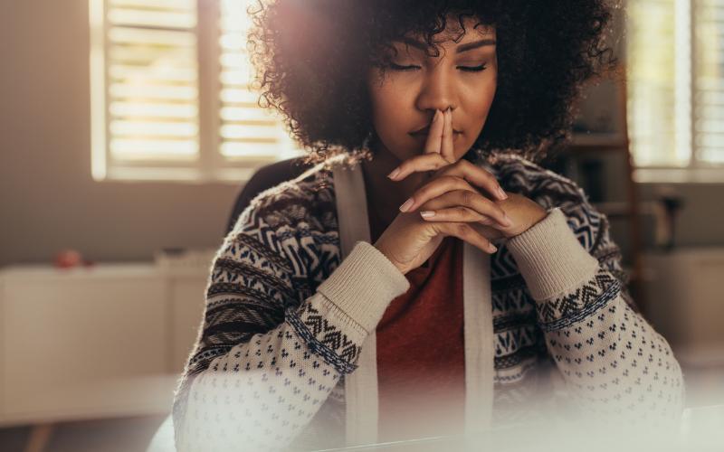 Woman with ADHD contemplating change, eyes closed, fingers to forehead.