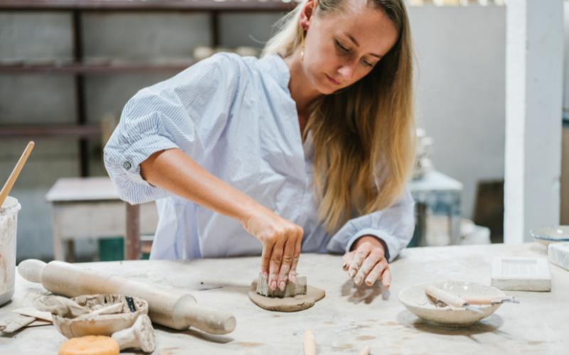 Woman crafting pottery, focusing to slow time down with art.