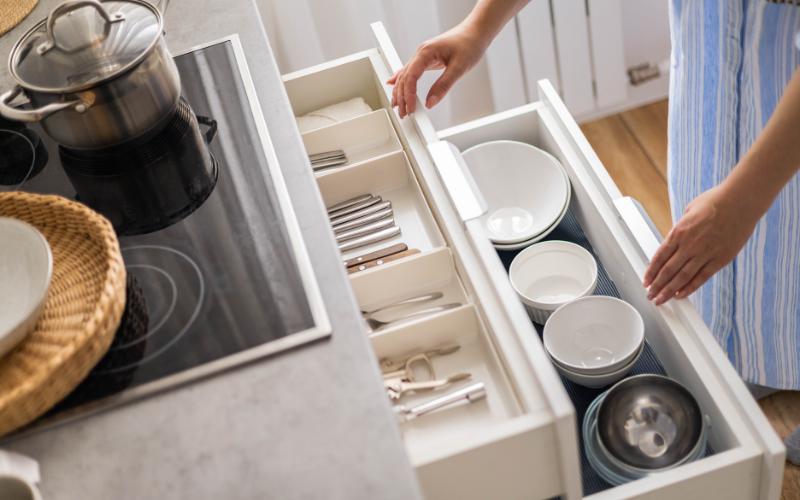 Open kitchen drawers with organized bowls and silverware, simplifying transitions.