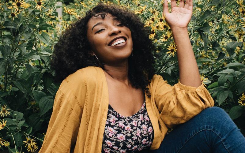 Smiling woman with curly hair and yellow cardigan, representing a play personality type.