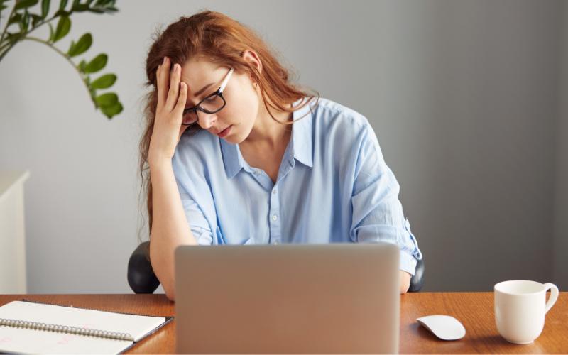 woman at desk looking stressed