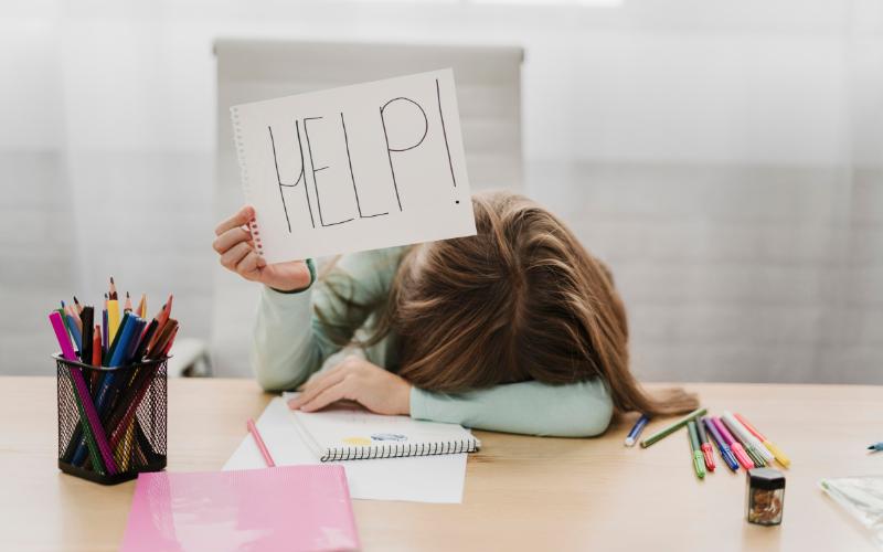 woman at desk holding help sign