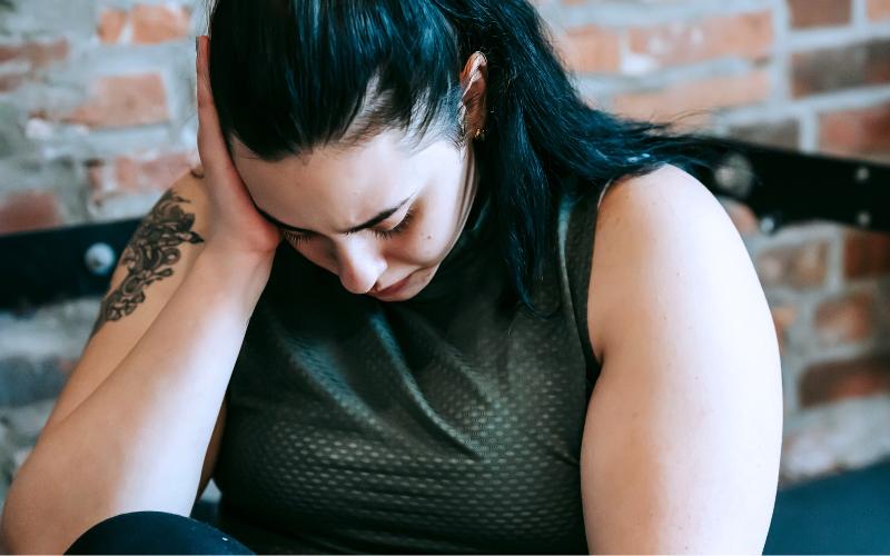 Woman looking down with hand on her head, symbolizing the need to stop beating yourself up.