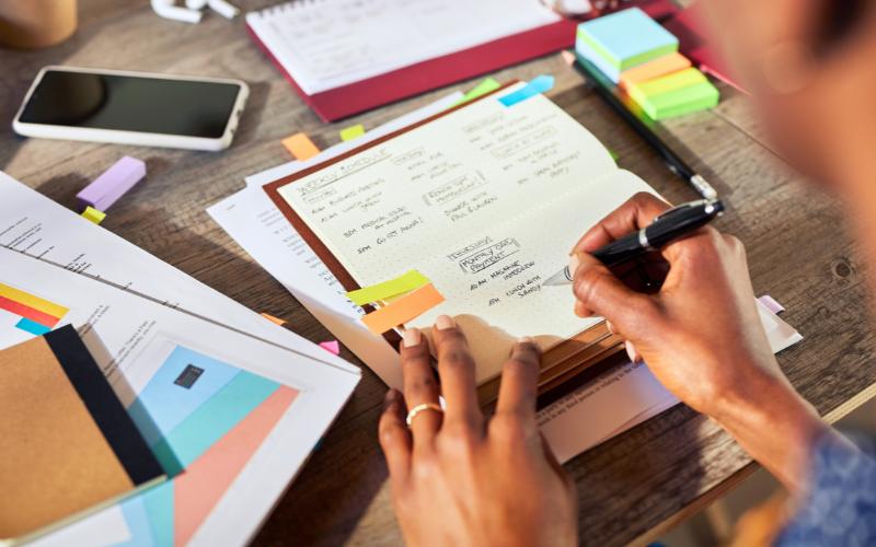 Person writing in planner with ADHD life hacks and to-do lists.