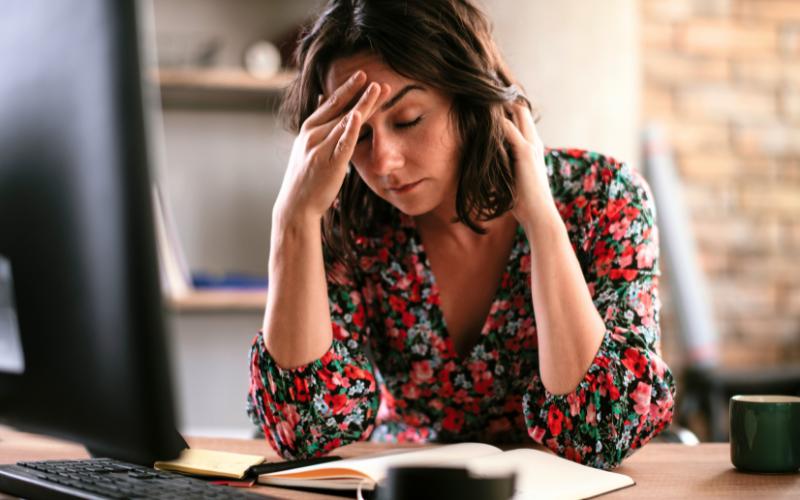 Woman with social jet lag looks stressed at her desk.