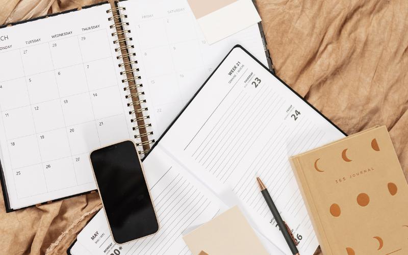 Planner, phone, and journal on a desk, symbolizing productivity and organization.