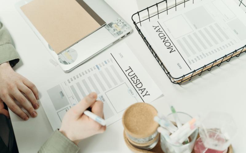 Planner pages for Monday and Tuesday, tools, and laptop on a desk, for ADHD productivity.