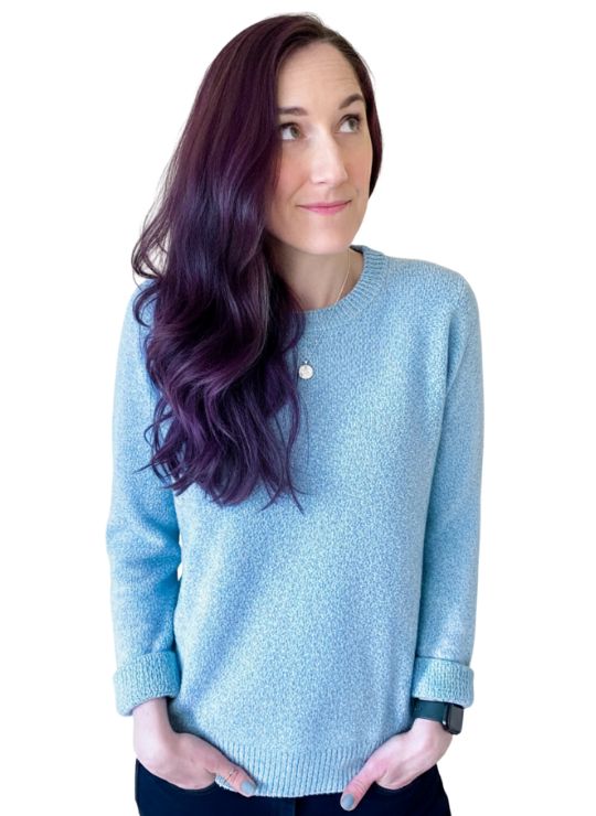 Woman with purple hair wearing a blue sweater.