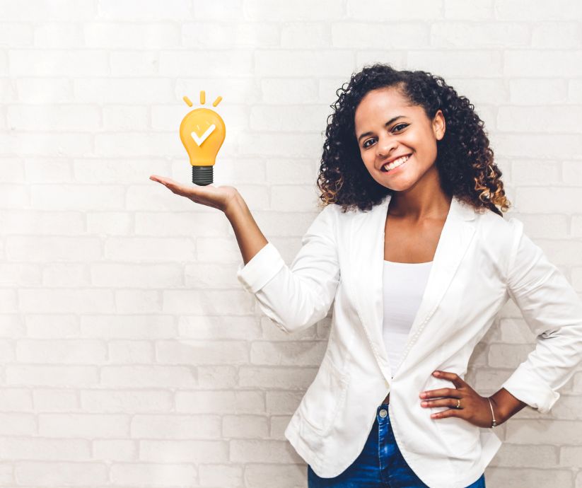 Woman holding a lightbulb with a checkmark, representing ideas related to ADHD object permanence.