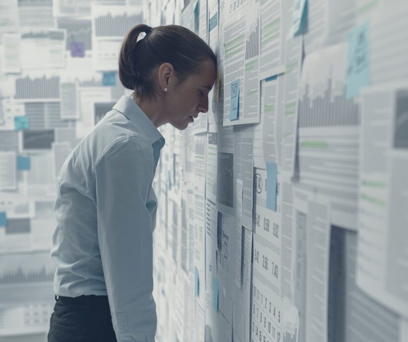Woman overwhelmed by papers on a wall, symbolizing doing everything for everyone.