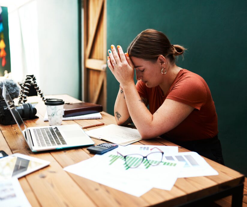 Woman with head in hands, struggling to get started with ADHD work